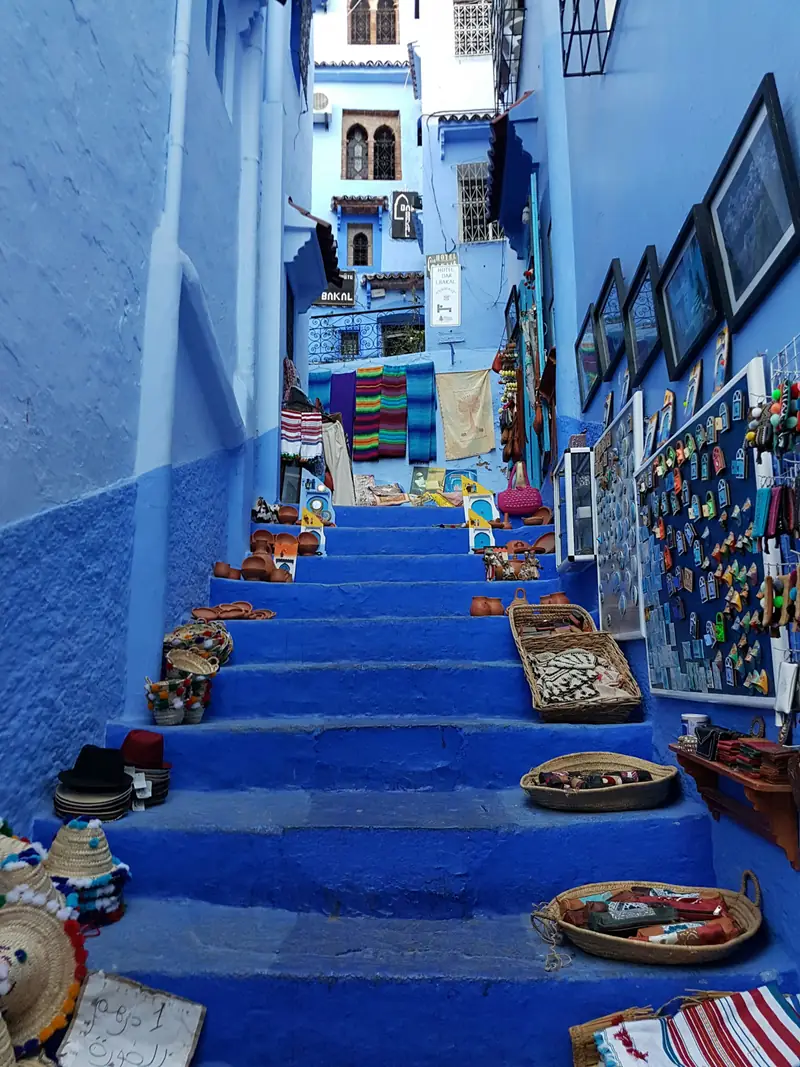 Scalinata blu di Chefchaouen con cesti e tessuti colorati